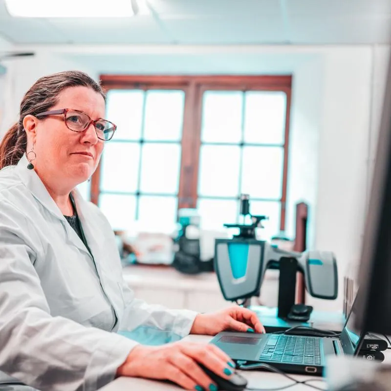 A researcher in a lab coat on a computer