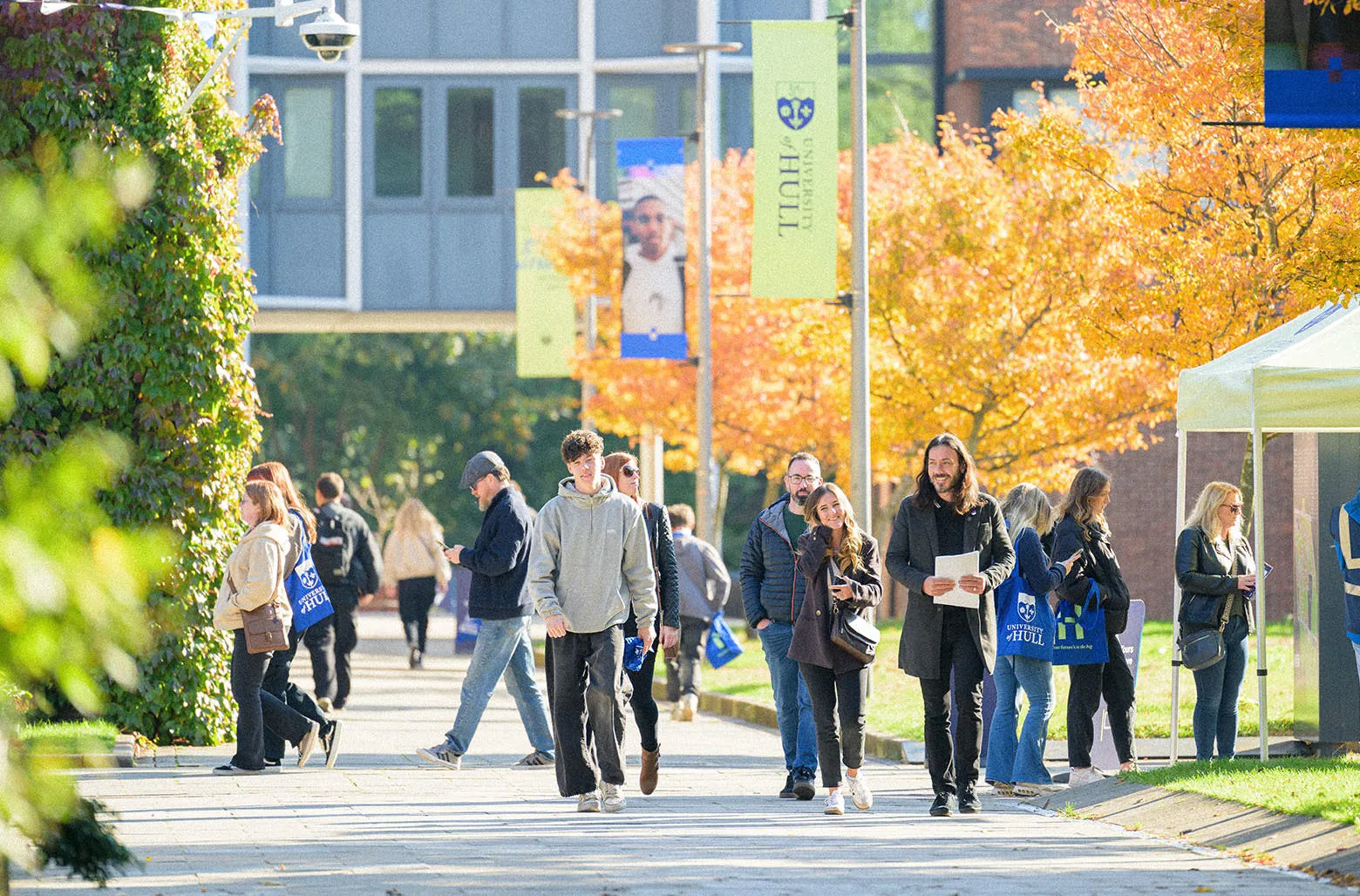 A large group of prospective students wandering campus on a sunny open day