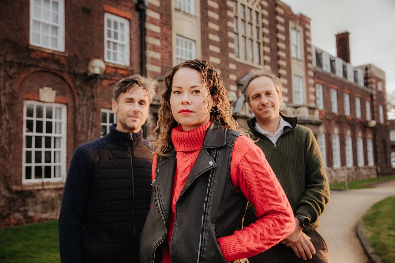 Three of Hull’s academics stand confidently together in front of an old red brick building