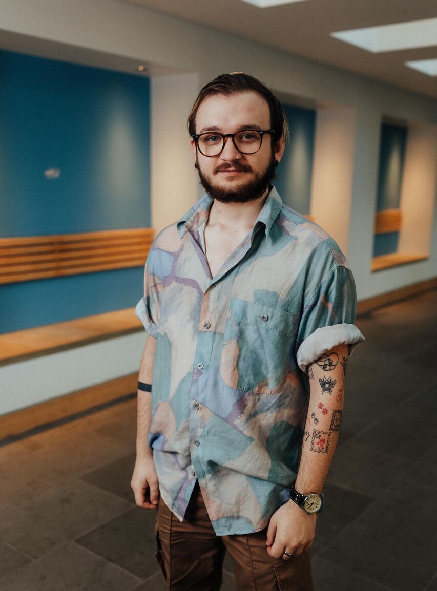 Three of Hull’s students stand confidently together in front of blue walls and wood panelled seating