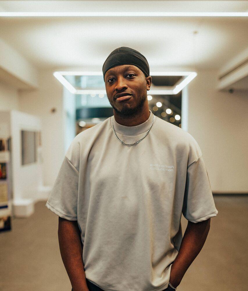 A male student stands confidently under modern lighting in the Library's foyer