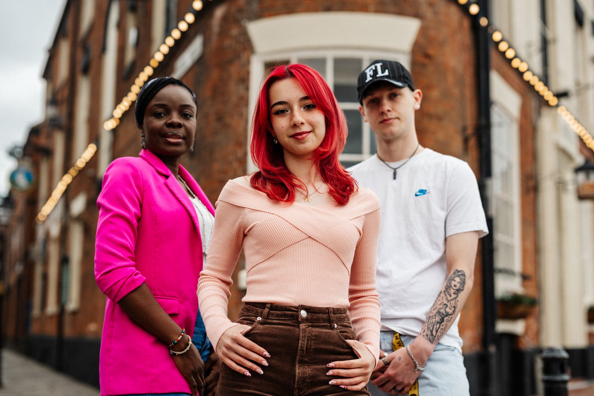 Three of Hull’s students stand confidently together in front of a dramatic old pub building on Hull's Marina