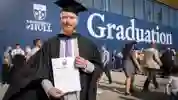 Gowned student holding his graduation certificate