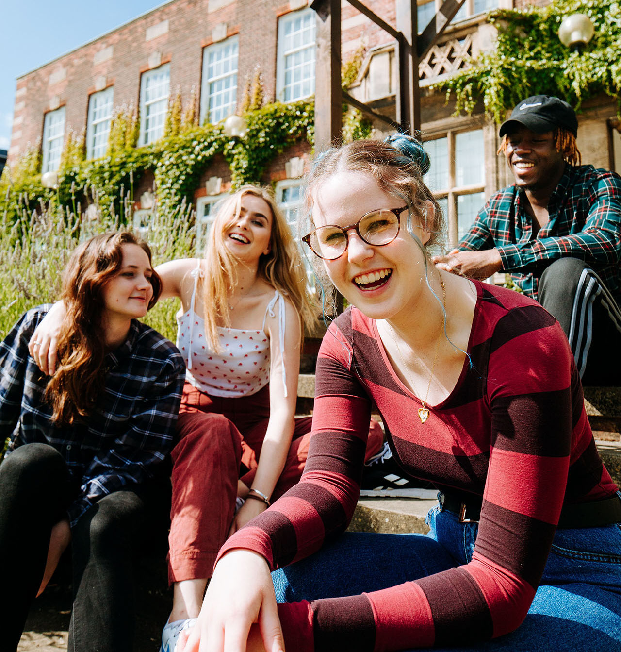 Four students laughing together on University of Hull campus.