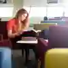 student reading books in a library seating area