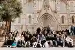 A large group of students sitting on the steps outside a cathedral in Barcelona