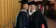 Two female students posing in their graduation cap and gowns