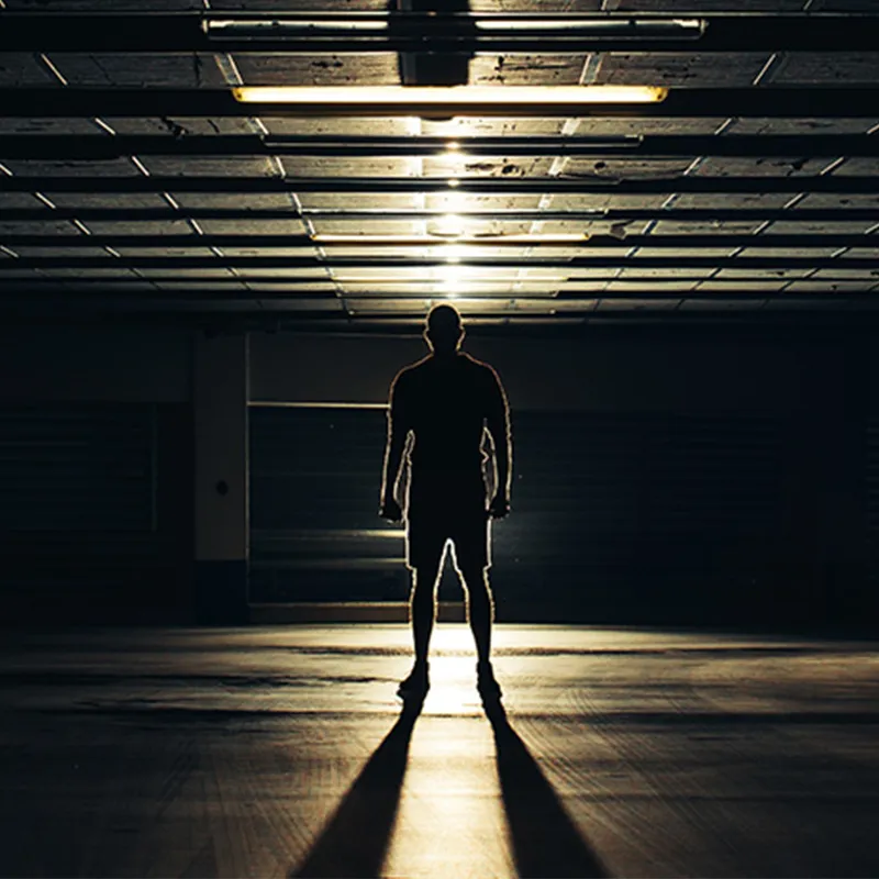 Man stood in shadow in an empty room