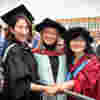 An academic poses with two graduands on their graduation day in Hull