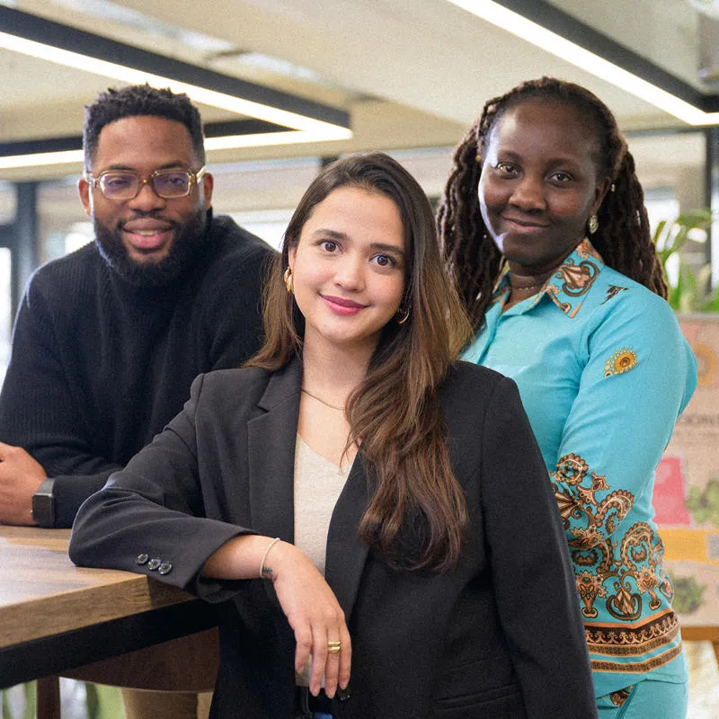 Three students leaning on a table and posing