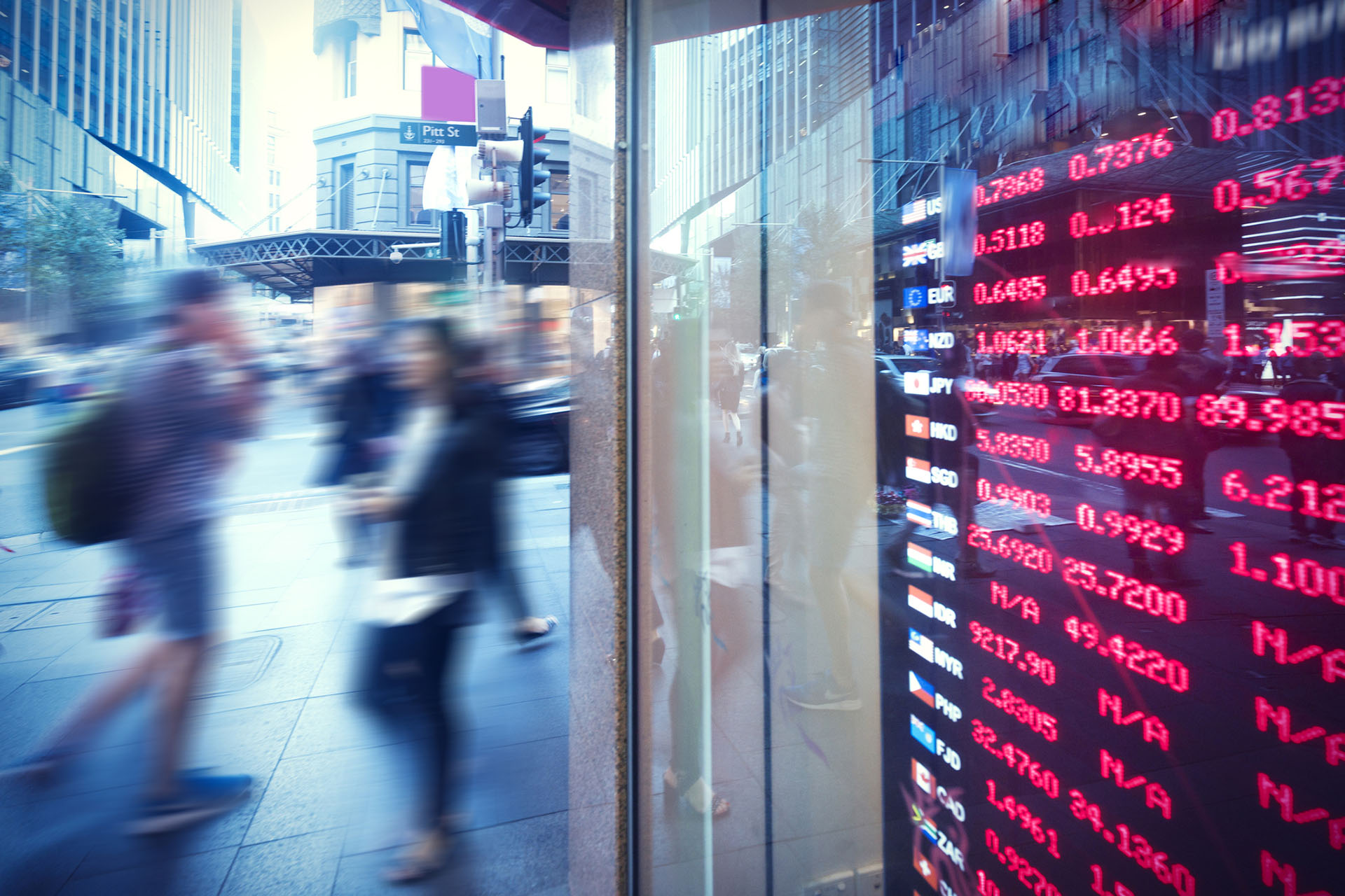 Stock market figures shown in window with blurred pedestrians