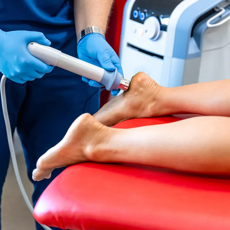 A clinician administers shockwave therapy to a patient's foot