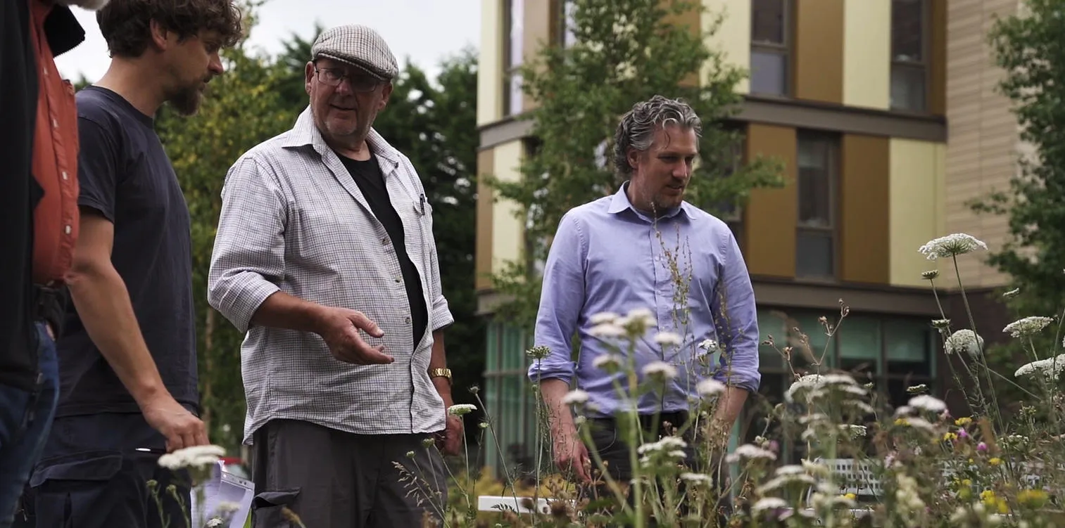 People gather by a flower bed as part of our SuDSlab campus tour