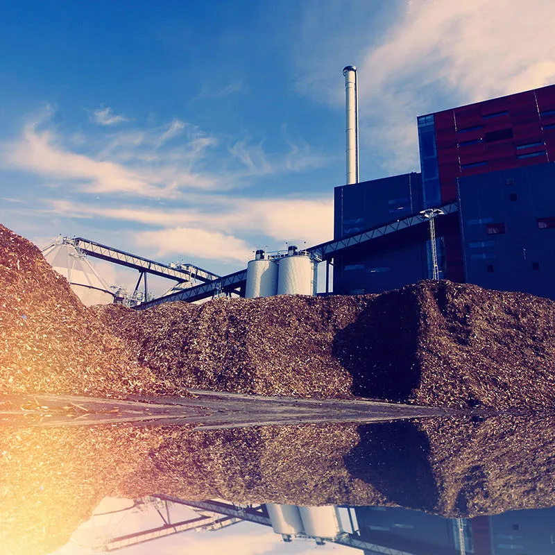 A pile of wood chips in front of an industrial building