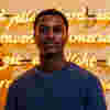 A student stands in front of gold illuminated neon writing, part of an artwork in Ferens Art Gallery