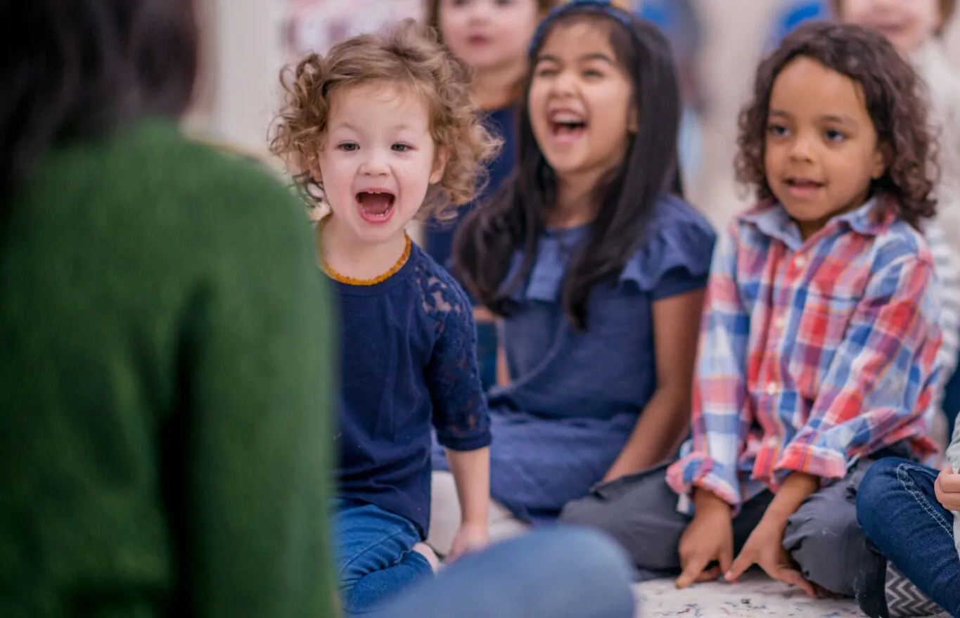 children sat on a playmat together listening to a story